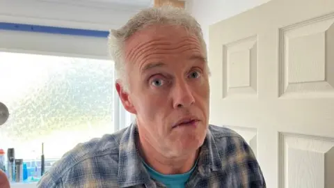 Andrew Turner/BBC Dale Burrage standing in the doorway to his bathroom where the problem emanated.