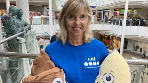 Juliette Rayner standing on the upper level at Cribbs Causeway holding two large cuddly toys