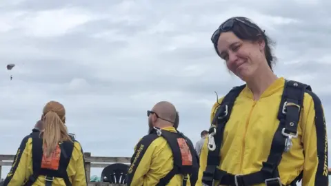 Scott Armstrong Belinda wearing a yellow safety gear suit smiling with sunglasses on her head.