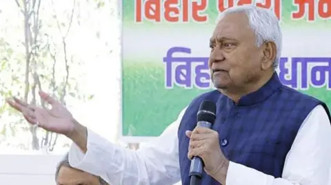 Bihar chief minister Nitish Kumar, wearing a blue sleeveless jacket over a white kurta, speaks at an event in Bihar's capital city Patna, after sweeping victory in the Assembly polls in November 2025.