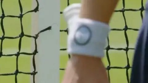 A hand next to a hole in a tennis net