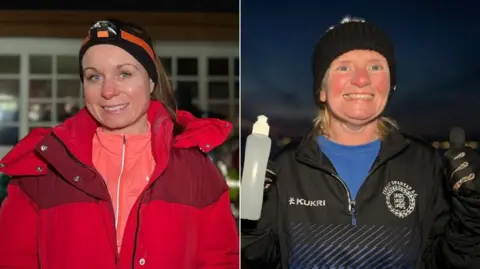 Carolyn is wearing a red coat with a pink zip-up running top under it. She has a head torch strapped to her head and her long light brown hair is tied into a ponytail as she smiles at the camera.  Joan is wearing black sports jacket with a Jersey Spartans logo on it and a blue running top under it. She has black gloved on and is holding a water bottle in one hand as she gives the thumbs up to the camera.