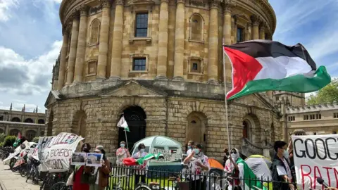 BBC Protesters with banners and a Palestinian flag flying outside the Radcliffe Camera