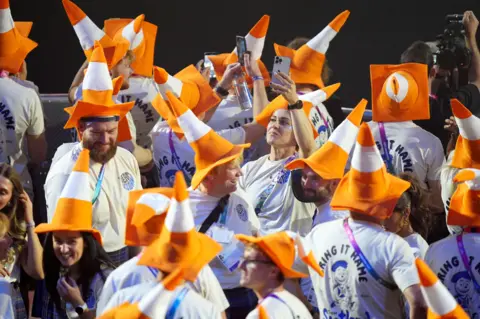 PA Media A crowd of people in T-shirts and traffic cones on their heads.