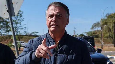 Brazil's former President Jair Bolsonaro gestures as he arrives to the State Secretariat of Penitentiary Administration headquarters in Brasilia, Brazil