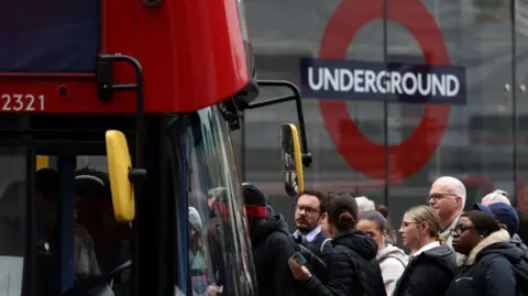 Getty Images File image showing commuters attempting to board a red London bus outside Victoria train station in London in 2022, with the underground roundel visible in the background