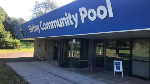 The outside of Birtley Pool with a sign outside and the swing doors open 