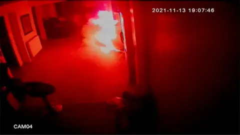 A hoverboard is ignited in flames in the corner of a room.
