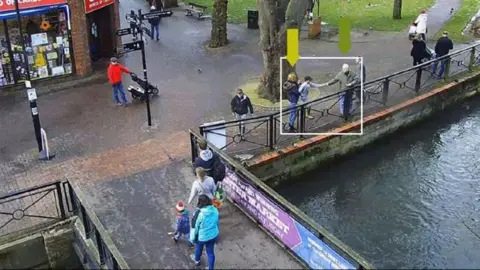 Handout CCTV image of a boy reaching out near a duck pond take something from Sergei Skripal. Other people are walking past.