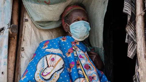 A displaced woman wears a mask as she sits outside her shelter in Bunia, the Democratic Republic of Congo. Photo: 28 May 2026 