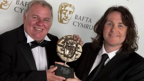 BAFTA Cymru Andrew Jenkins dan Peter Watkins Hughes memegang penghargaan BAFTA Cymru 