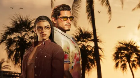 A screenshot from GTA 6 shows main characters Lucia and Jason standing back-to-back against a palm tree-lined sunset. She wears tinted glasses, her long dark hair styled in side-parted cornrows. She wears a tan suede jacket over a string bikini top. He also wears tinted shades and a white shirt with an oversized collar and floral pattern.