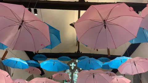 Pink and blue umbrellas hanging from a church ceiling to represent baby loss 