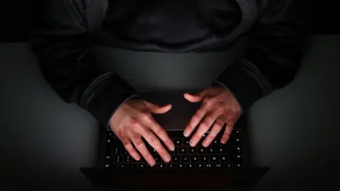 PA Media A pair of hands are positioned over a laptop keyboard on a desk. The identity of the person remains anonymous as only their arms are visible in the image.