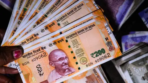 AFP via Getty Images A woman holding rupee notes