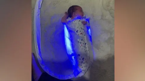 Supplied A baby wrapped in a blankety which is emitting blue light
