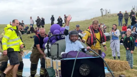 A group of people pushing a soap box that is taking part in a soap box competition in Berkeley.