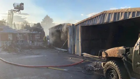 Derbyshire Fire & Rescue Service An image of smoke emerging from garages behind a bungalow which caught fire