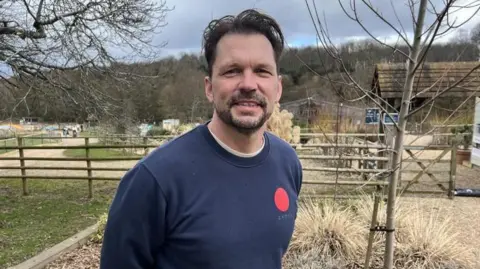 Stuart Howells/BBC Jimmy Doherty stands with farm fences and trees behind him