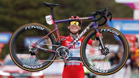 Demi Vollering lifts her bike in the air after winning stage eight of the Vuelta Femenina in 2024