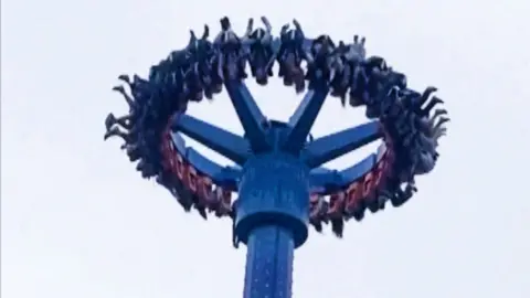 People near  dangling upside down   connected  amusement parkland  ride