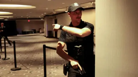 Secret Service agent gestures as a shooter opens fire during the annual White House Correspondents' Association dinner in Washington, D.C
