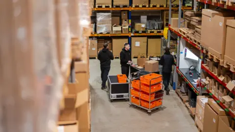 Diamond Logistics A warehouse filled with boxes. Three men are standing around. 