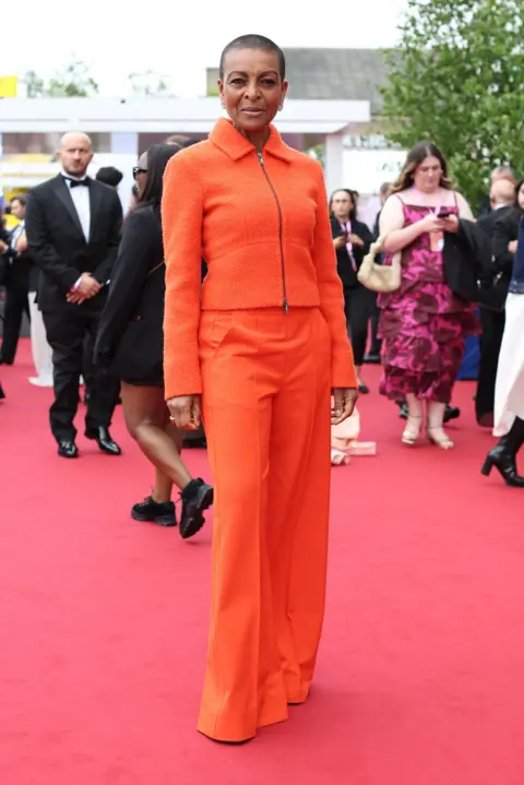 Getty Images Adjoa Andoh in bright orange trousers and a matching zip-up top