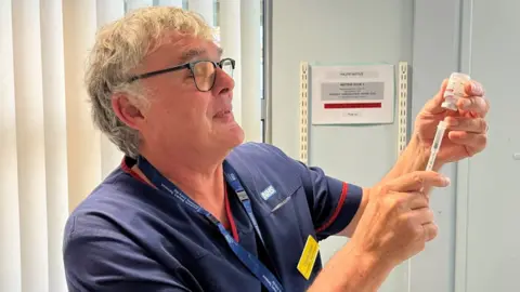 David Drew, from Somerset Foundation Trust Vaccination Team, preparing a vaccination.