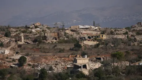 Neha Sharma/BBC Destroyed buildings and piles of rubble are seen on a hillside in southern Lebanon.