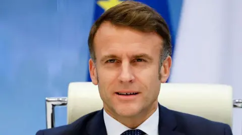 AFP French President Emmanuel Macron in a blue suit and white shirt