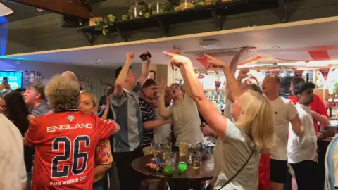 People are singing and have their arms raised.