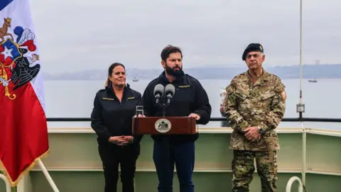 Chilean President Gabriel Boric delivers a speech during the inaugural Antarctic mission of the icebreaker Almirante Vial, with Defence Minister Maya Fernández and Admiral Juan Andrés de la Maza standing beside him.