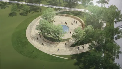 NDSWM An artist's impression of a circular memorial design featuring stone pathways and a central water feature surrounded by trees. People are walking along the curved paths, and the memorial is set within a grassy park area with a road visible at the top of the image.