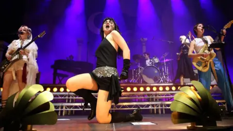 Adam Berry/Getty Images (L-R) Emily Roberts, Abigail Morris and Lizzie Mayland of The Last Dinner Party perform during a concert at Uber Eats Music Hall on November 07, 2024 in Berlin, Germany. 