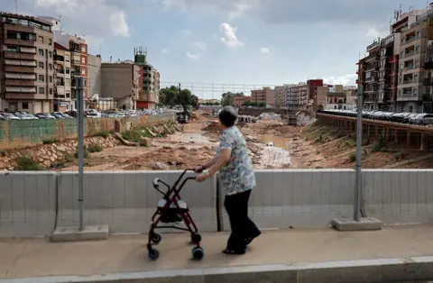 Getty Images A woman walks on a bridge overlooking a riverbed full of mud