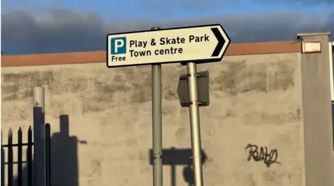 John Wimperis A car park sign pointing towards a skate park