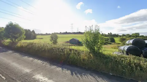 The view from Whitehall Road West over green fields with pylons