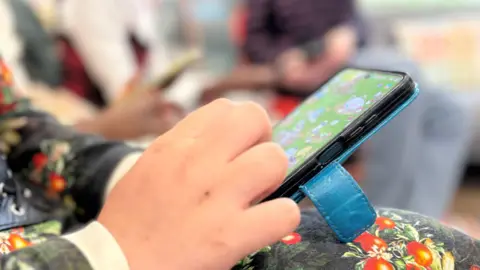 A child's hand playing a game on a smartphone