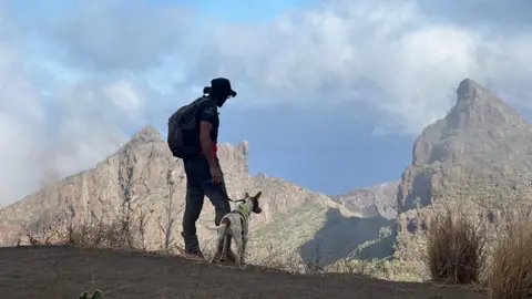 Nick Garnett/BBC A man and a dog look over a huge ravine in Tenerife