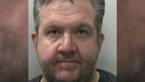Devon and Cornwall Police A mugshot of Hopper. He has grey hair and blue eyes and is looking steadily at the camera.