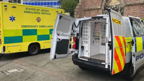 BBC An Jersey ambulance next to a Jersey police van.