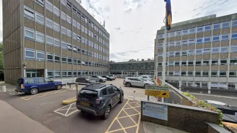 a car park with two concrete six-storey buildings either side and a flag in the foreground 