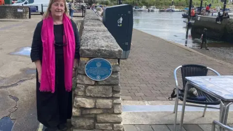 Brian Farmer/BBC Jacqui England standing next to plaque