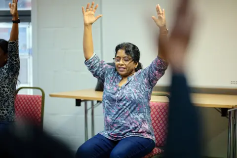 Meera mengangkat tangannya selama sesi yoga dan meditasi di Croydon