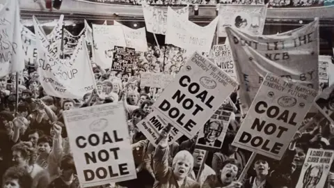 The miners' strike, with signs held up saying "coal not dole"