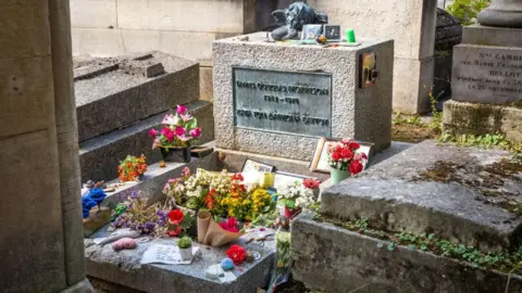 Getty Images Flowers, photos and mementoes are laid on the grave of Jim Morrison, which reads 'James Douglas Morrison 1943-1971'
