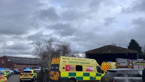 Supplied Multiple police, fire and ambulance service vehicles are parked at the farm, some with blue flashing lights.