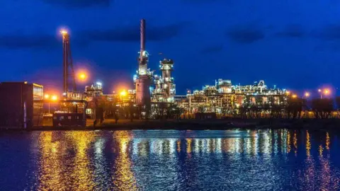 North Sea Midstream Partners The St Fergus gas terminal in Aberdeenshire, photographed at night, with infrastructure lit up, and reflected in water.