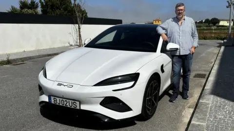 Portuguese business executive Luis Costa stands next to his BYD stamp.